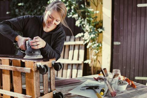 Wanita menggiling rak buatan luar yang dibuat dari palle - upcycling