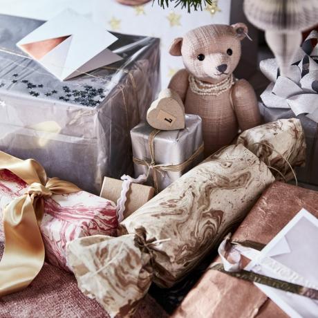 close up hadiah di bawah pohon natal boneka beruang kecil dan perak dan emas terbungkus kadoberharga berikan sentuhan glamour pada pembungkus kado dengan menggunakan kertas berbahan perak, tembaga, dan marmer selesai