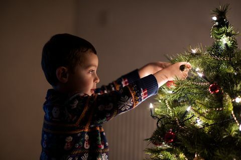 Anak laki-laki mendekorasi pohon Natal di rumah