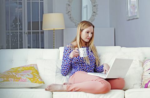 Wanita di laptop duduk di ruang tamunya