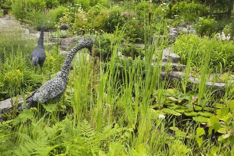 Kolam hias dengan patung-patung kawat di taman halaman belakang yang indah di musim semi