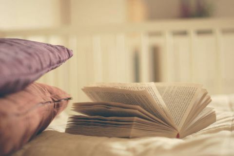 Buku terbuka dan dua bantal di tempat tidur