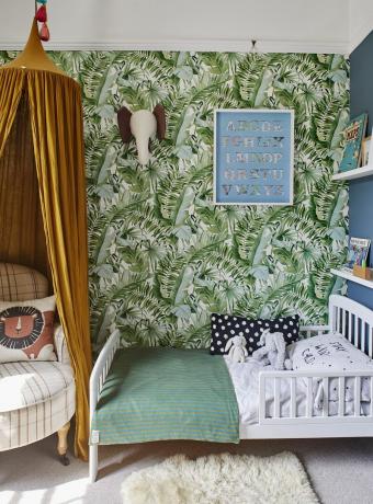 kamar tidur anak dengan wallpaper motif palem tropis dan kanopi kuning