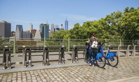 Wanita mengambil sepeda di depan kaki langit Manhattan di New York City