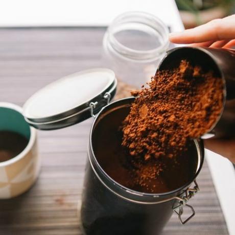 kebun kopi bubuk tangan yang dipotong menuangkan kopi bubuk ke dalam wadah yang dapat digunakan kembali