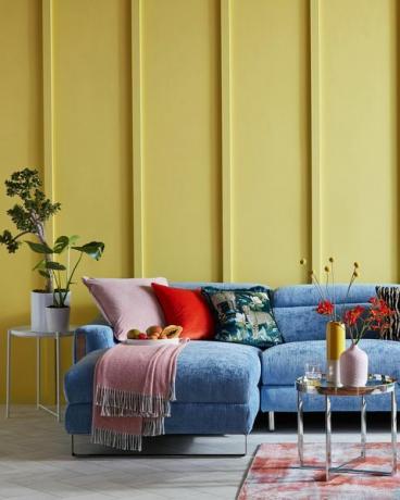 ruang tamu yang cerah dengan dinding berpanel kuning dan sofa biru