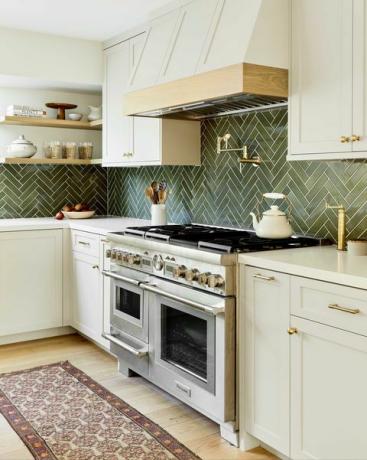 dapur, lemari krem ​​dengan meja marmer krem, backsplash ubin hijau, pelari lantai, oven stainless steel, perangkat keras emas