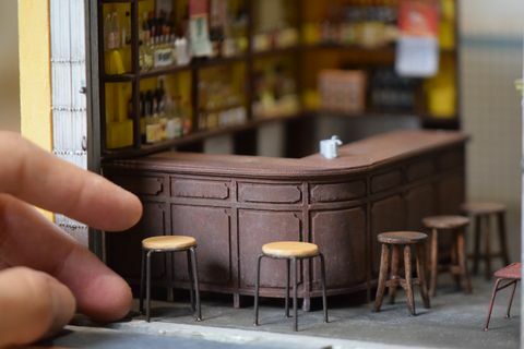 closeup replika miniatur bar, dengan kursi bar dan tangan manusia untuk timbangan