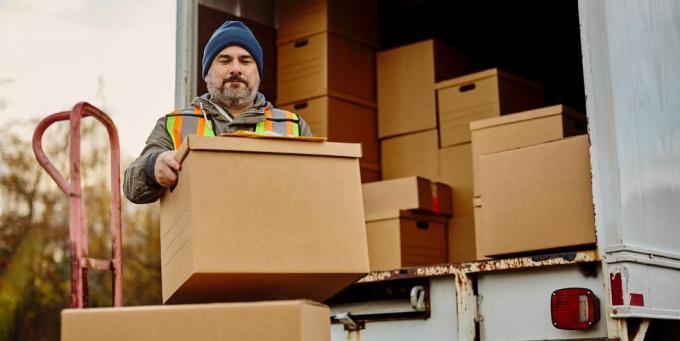 pekerja laki-laki membongkar kotak kardus dari van pengiriman