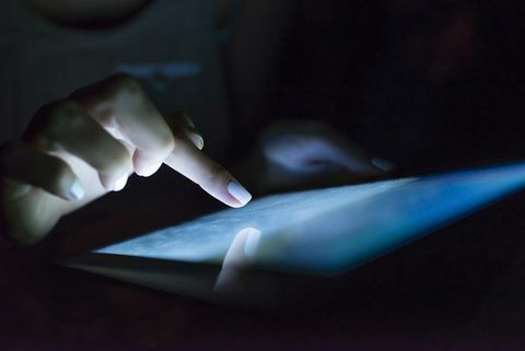 Tangan menggunakan tablet digital pada malam hari