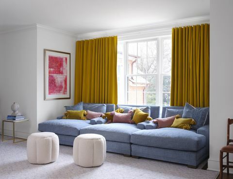 sofa biru, tirai kuning, bantal merah muda dan kuning