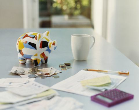 Piggybank, Mata Uang Inggris, Kalkulator, Kwitansi dan Mug di atas Meja