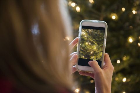 Wanita memotret pohon Natal dengan ponsel