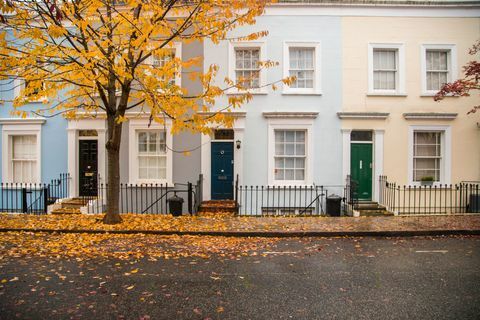 Rumah-rumah di lingkungan Notting Hill dengan façade warna pastel dengan komposisi yang bagus tanpa mobil dan pohon dengan daun musim gugur di tanah di kota London. Kerajaan Inggris, Eropa.